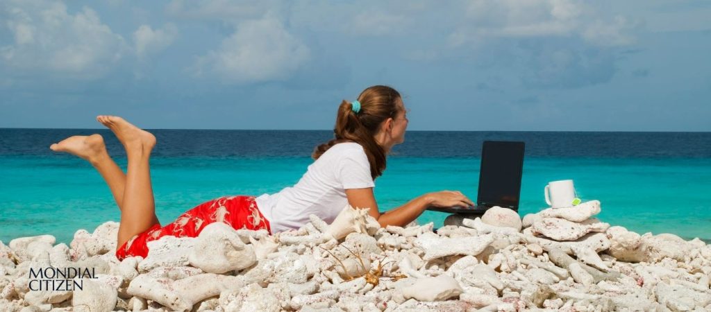 Remote worker using a laptop by the sea, representing the Spain Digital Nomad Visa lifestyle for non-EU professionals relocating to Spain.